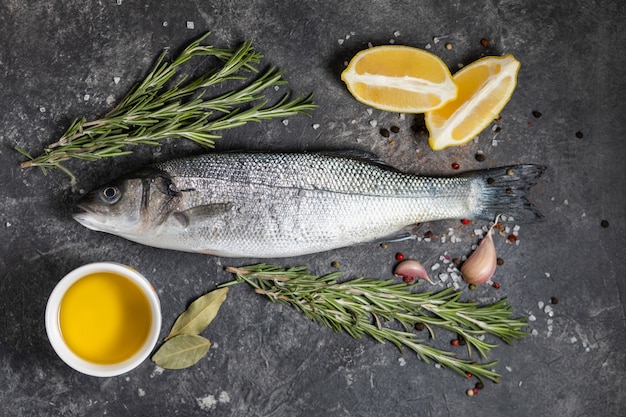 Photo fresh fish seabass and ingredients for cooking, lemon and rosemary.