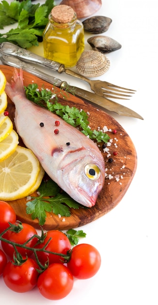 Свежая рыба и морепродукты с кусочками лимона, помидорами и зеленью