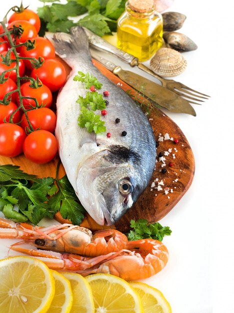 Fresh fish and seafood with lemon pieces, tomatoes and herbs