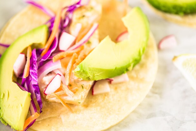 Fresh fish tacos with cod and purple cabbage on a white corn tortillas.