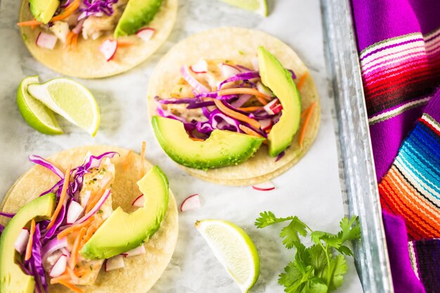 Foto tacos di pesce fresco con merluzzo e cavolo viola su tortillas di mais bianco.