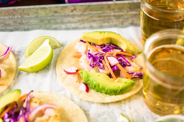 Fresh fish tacos with cod and purple cabbage on a white corn tortillas.