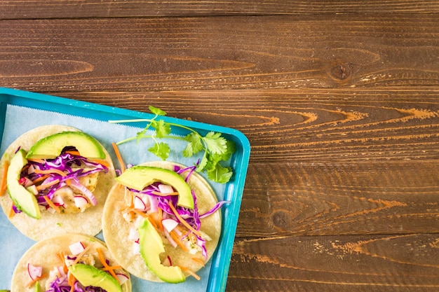 Photo fresh fish tacos with cod and purple cabbage on a white corn tortillas.