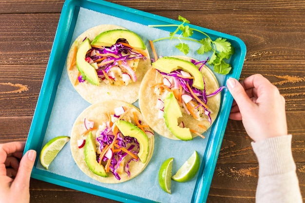 Fresh fish tacos with cod and purple cabbage on a white corn tortillas.