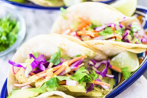 Fresh fish tacos with vegetables and guacamole salsa on a white corn tortillas.