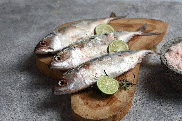 fresh fish on wooden board with limerosemary and himalaya salt