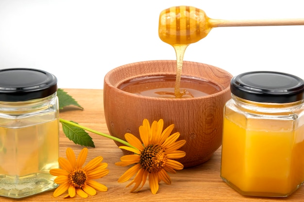 Fresh floral honey dripping from a spoon into a wooden plate on a white background organic vitamin health food