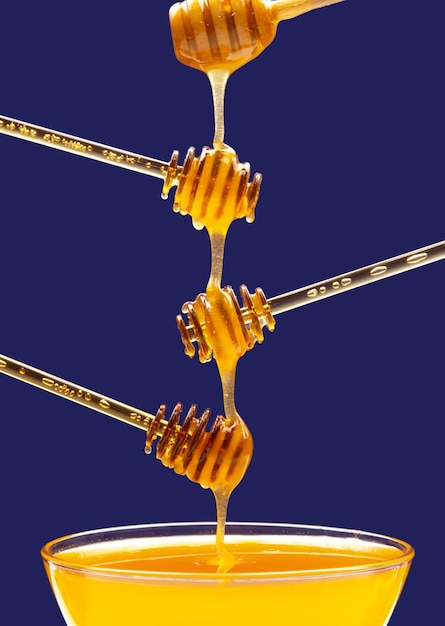 Фото Свежий цветочный мед капает из ложки в ложку на синем фоне органические витаминные продукты