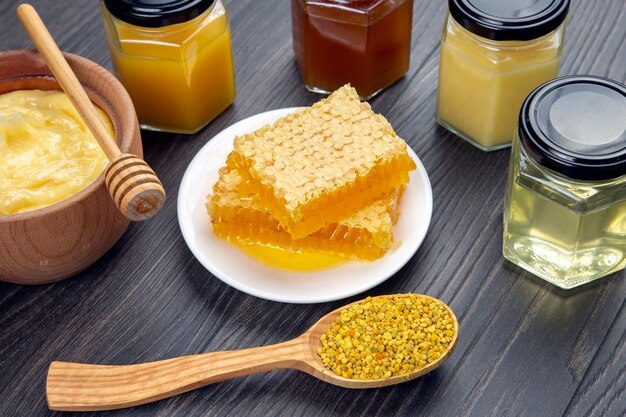 Fresh flower honey of different varieties, pollen and honeycomb with spoons on a wooden background. Organic Vitamin Health Food