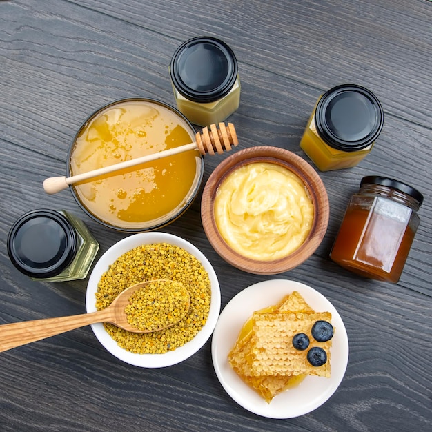 Fresh flower honey of different varieties, pollen and honeycomb with spoons on a wooden background. Organic Vitamin Health Food