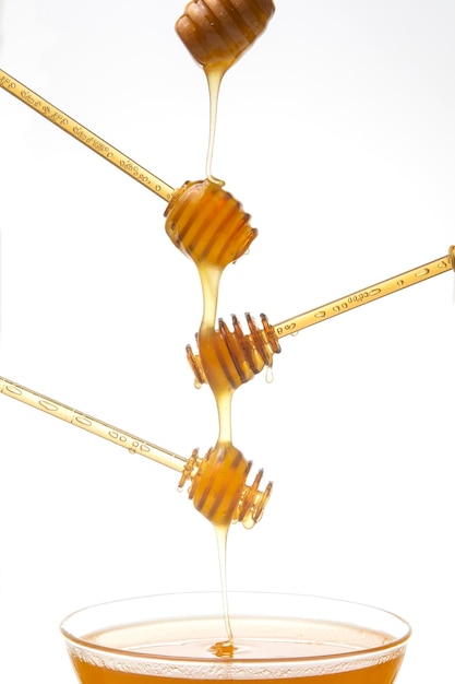 Fresh flower honey drips from a spoon into a spoon on a white background. Organic vitamin food.