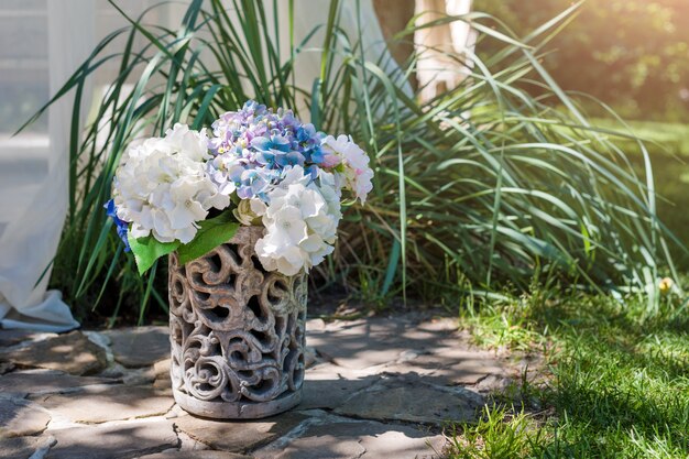 Fresh flowers arrangement in vase in the garden. Decorative bouquet for festive event.