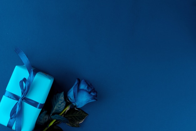 新鮮な花と古典的な青色の背景にリボン付きギフトボックス