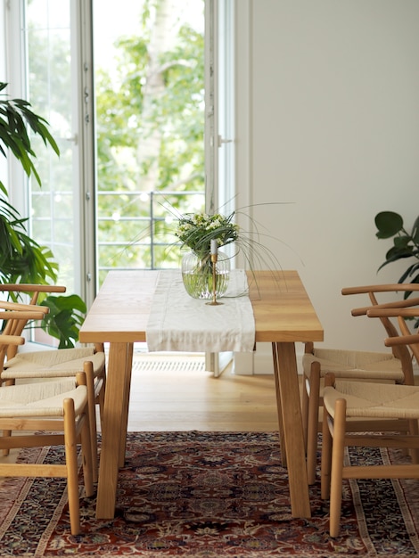 Fiori freschi in vaso di vetro che sta su una tavola di legno nell'interno bianco della sala da pranzo con tappeto orientale. interior design in stile minimal.