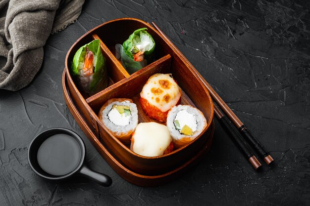 Fresh Food Portion in Japanese Bento Box with Sushi Rolls set, on black stone 