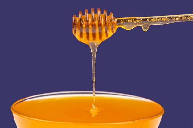 Fresh fragrant honey dripping from a spoon into a plate on a blue background. organic vitamin nutrition