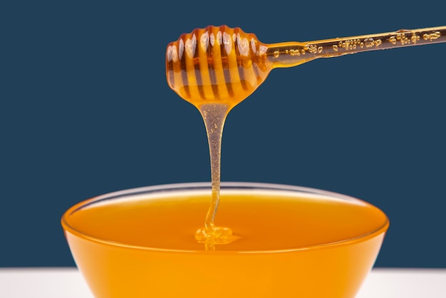 Fresh fragrant honey drips from a spoon into a plate on a colored background organic vitamin nutrition dessert food