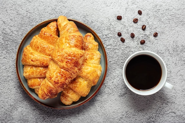 Fresh french croissants on plate blueberry jam honey cup of coffee on table