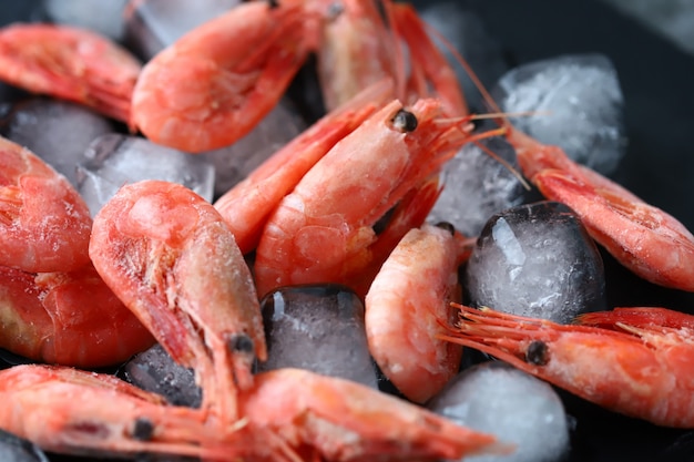 Fresh frozen shrimps with lemon on ice