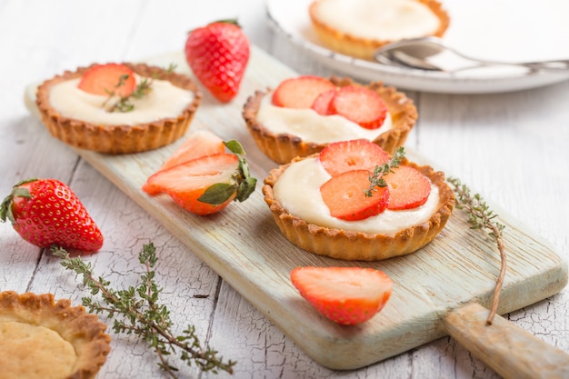 Fresh fruit and berry tart dessert on wooden . Delicious sweet cake with strawberries and cream. Strawberry tarts top view