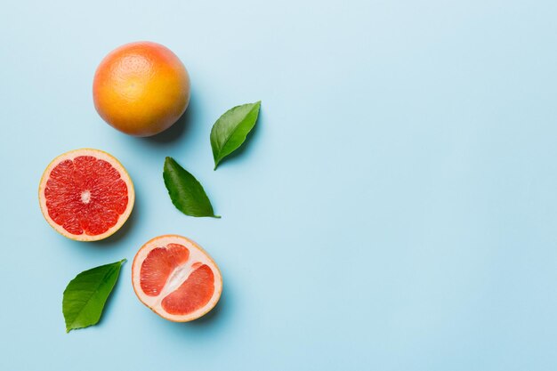 色付きの背景にジューシーなグレープフルーツのスライスが付いたフレッシュフルーツグレープフルーツ上面図コピースペースクリエイティブな夏のコンセプトコピースペースのある最小限のフラットレイの柑橘類の半分