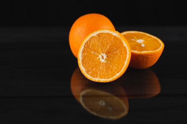 Свежие апельсины на черном деревянном фоне с отражением