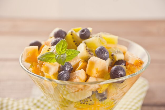 Fresh fruit salad in the bowl on the wooden table