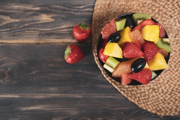 Салат из свежих фруктов вид сверху в миске на деревянном фоне концепция вегетарианской пищи БИО фрукты