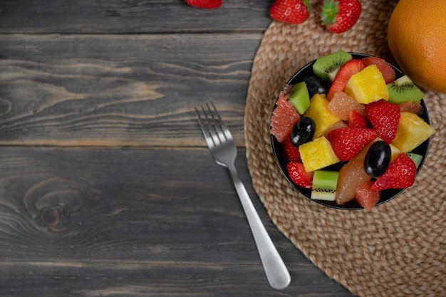 Fresh fruit salad top view in a bowl on wooden background vegetarian food concept BIO fruits