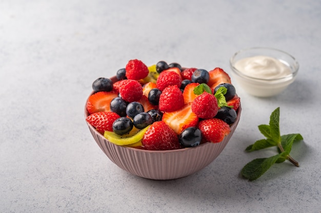 Fresh fruit salad with different ingredients with mint and sour cream