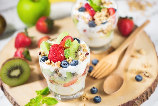 Photo fresh fruit salad with yogurt and berry in glass on wooden plate