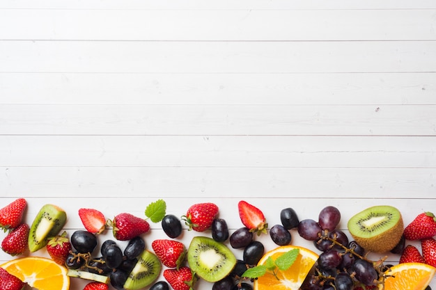 Fresh fruit strawberry kiwi grapes on white table with copy space.