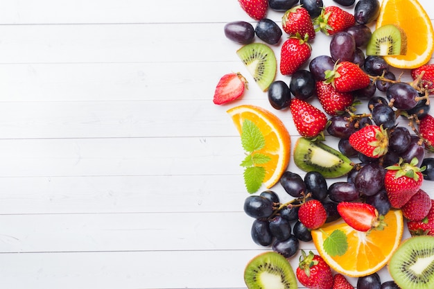 Fresh fruit strawberry kiwi grapes on white table with copy space.