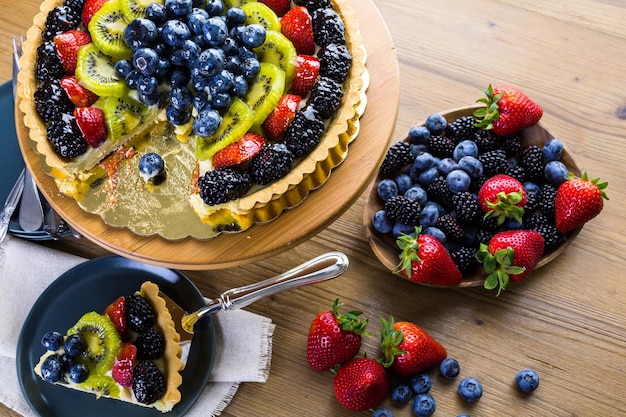 Fresh fruit tart on cake stand on wood table.