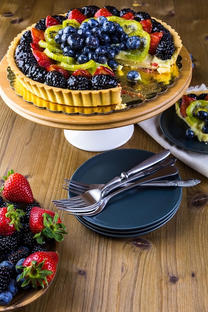 Foto crostata di frutta fresca su supporto per torta su tavola di legno.