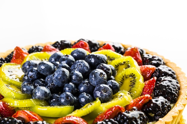 Crostata di frutta fresca realizzata in grande forma rotonda su sfondo bianco.