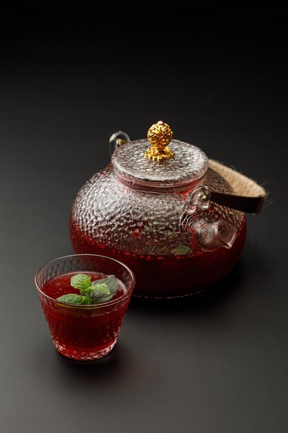 Fresh fruit tea in glass cup with teapot on background