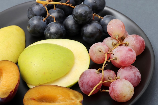 Fresh fruits grape plum apple pear in the plate