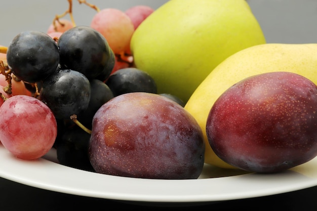 Fresh fruits grape plum apple pear in the plate