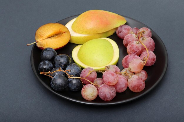 Fresh fruits grape plum apple pear in the plate