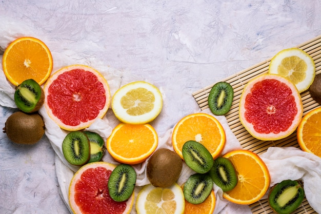 Fresh Fruits, Grapefruit, Lemon, Orange, Kiwi on a Light Stone background.