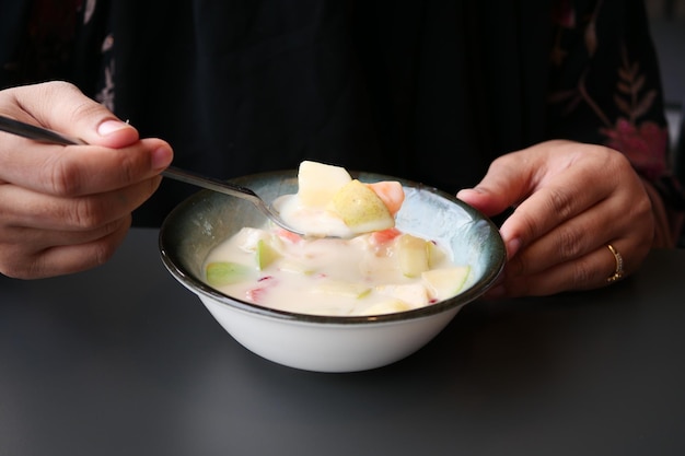 Fresh fruits mixed with yogurt in a bowl on table