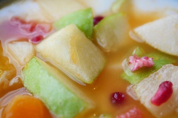 Fresh fruits mixed with yogurt in a bowl on table