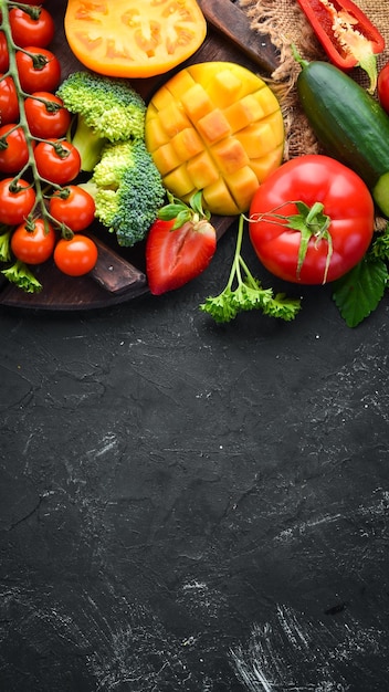 Fresh fruits vegetables and berries On a black background Banner Top view Free space for your text