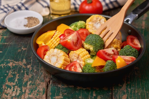 Photo fresh fruits and vegetables on a frying pan on an old wood background