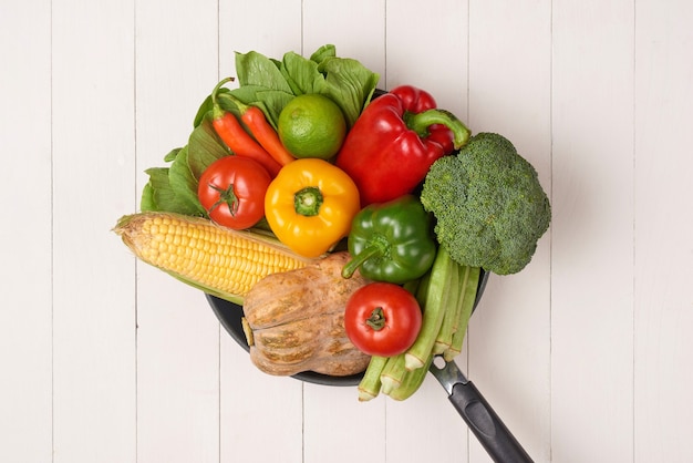 Fresh fruits and vegetables on a frying pan on an old wood background
