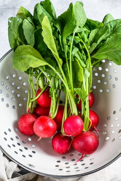 Fresh garden radish in a white colander. Farm organic vegetables. Top view