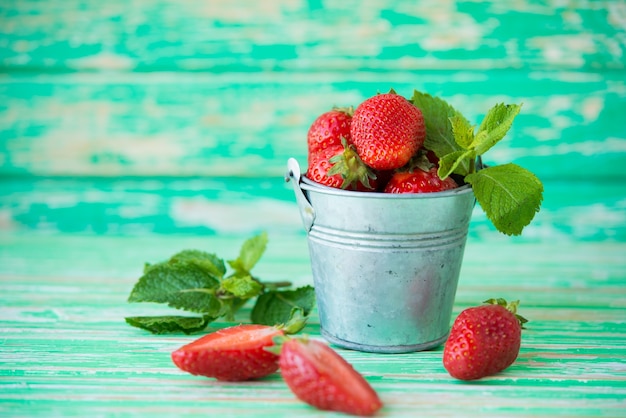Fresh garden strawberries in a bucket on a rustic background, selective focus, copy space