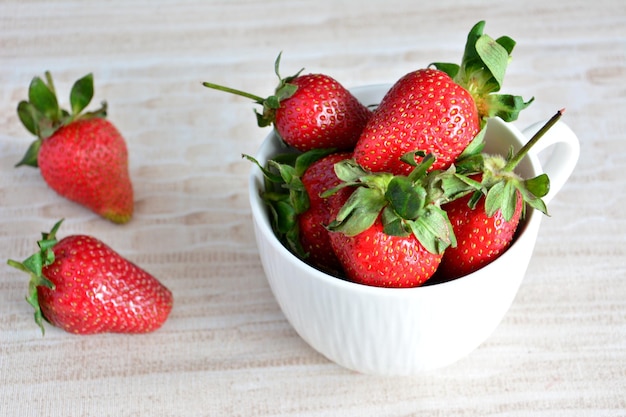 fresh garden strawberry in white cup on pastel background