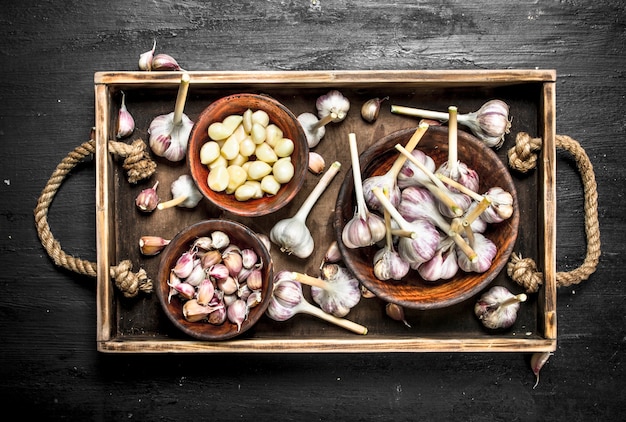 Fresh garlic in a bowl on a wooden tray.